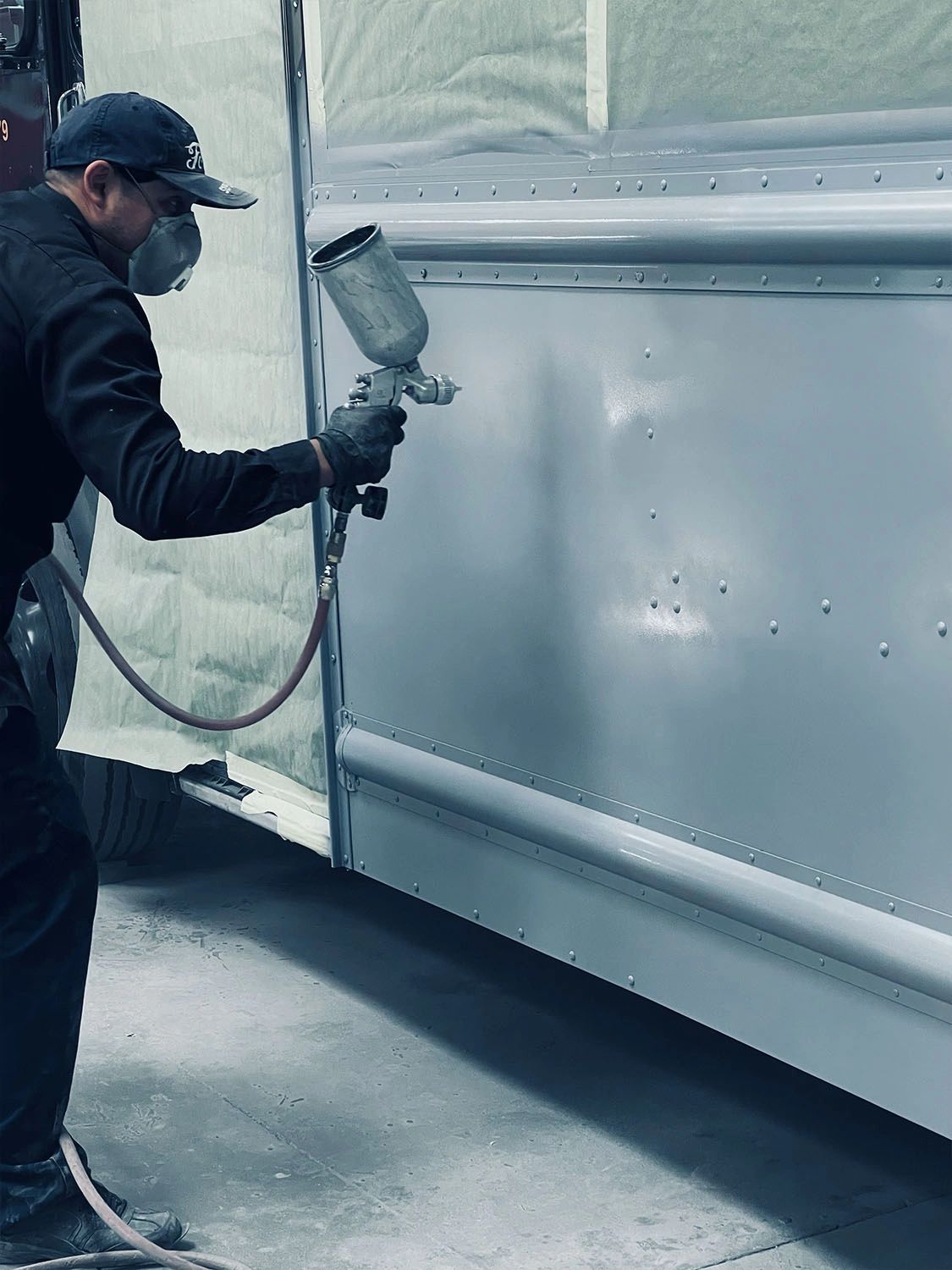 Advance Truck Painting technician spraying primer on a box truck